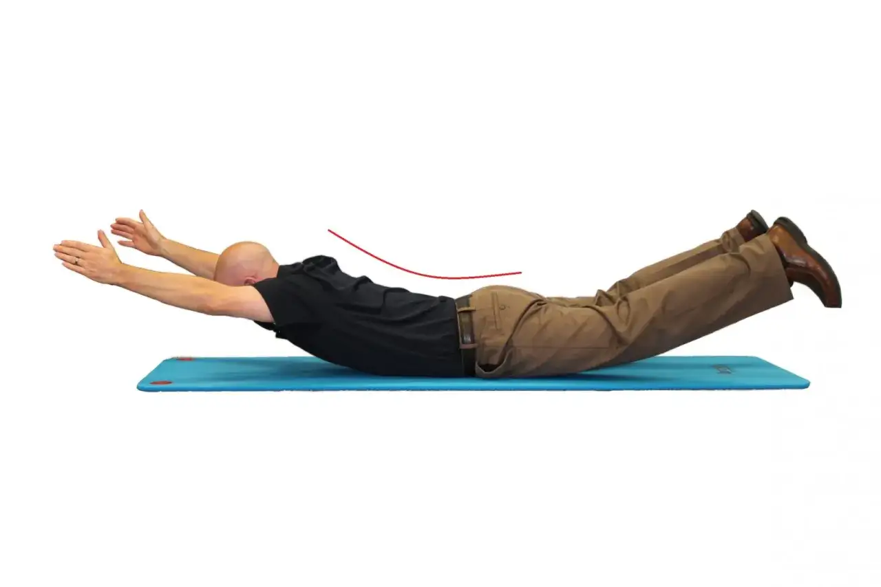 Hombre en colchoneta azul haciendo ejercicio de extensi&oacute;n lumbar, con brazos extendidos y piernas levantadas.