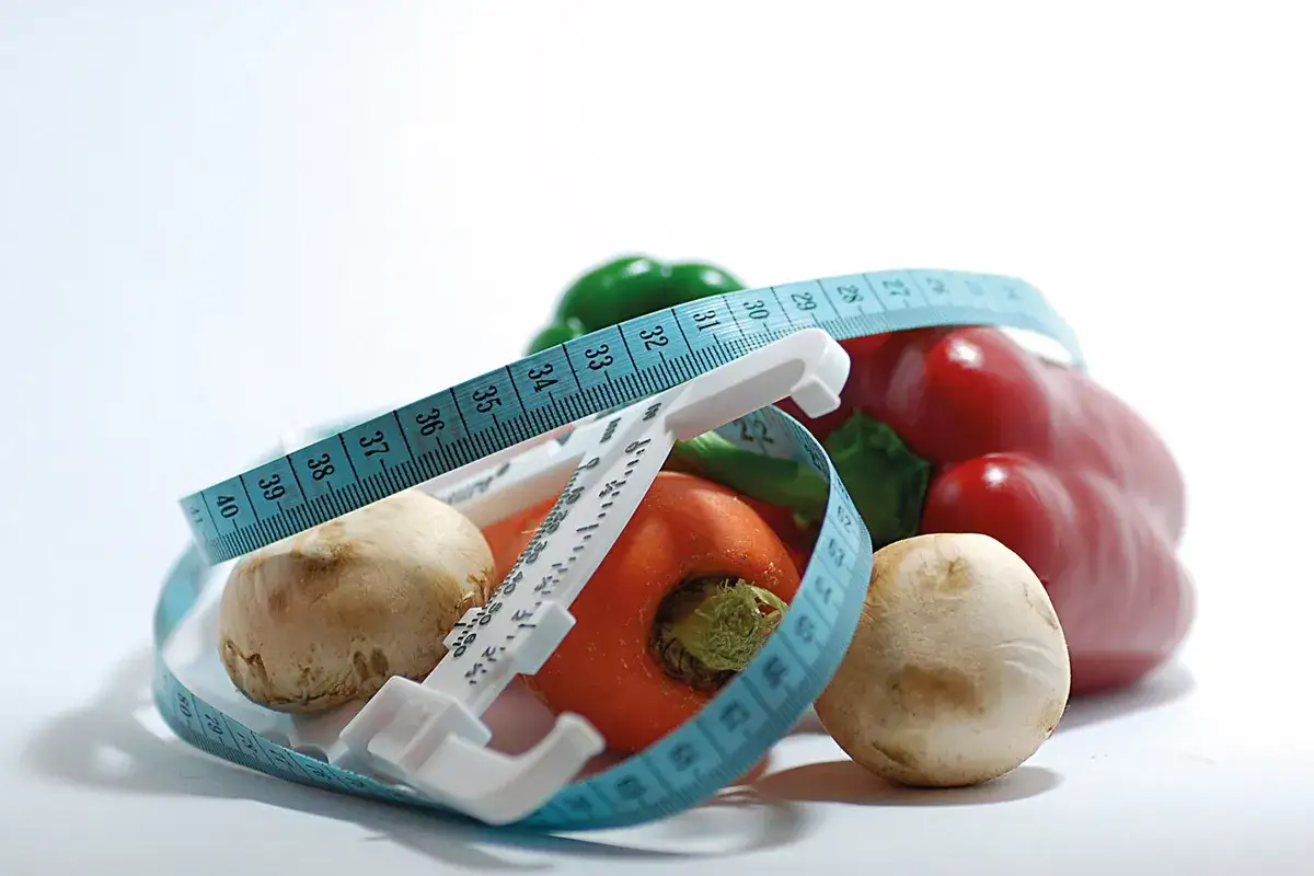 Verduras frescas y cinta métrica, símbolos de dietas milagro.
