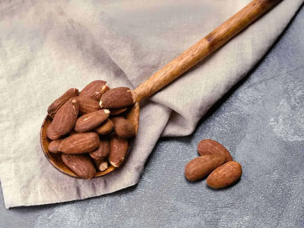 Cuchara de madera llena de almendras, destacando sus saludables propiedades.