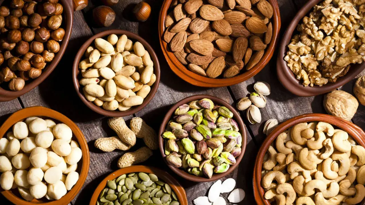 Variedad de frutos secos bajos en fodmap en cuencos: almendras, anacardos, nueces, pistachos, cacahuetes, avellanas y macadamias.