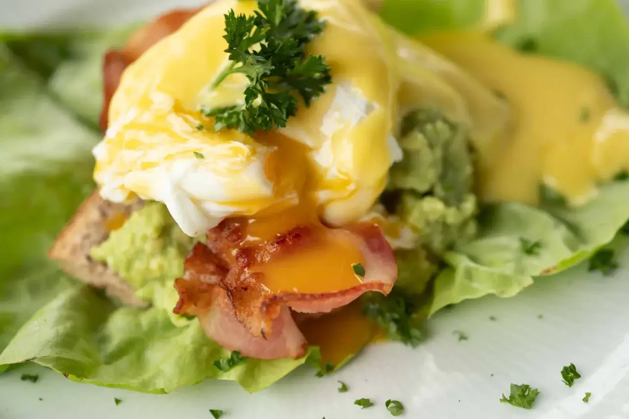 Huevos escalfados con aguacate, tocino y holandesa. Ideal para saber qu&eacute; comer para romper el ayuno intermitente 16/8.