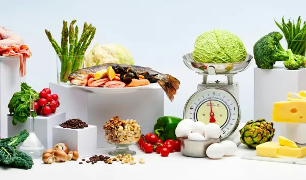 Variedad de alimentos bajos en carbohidratos: pescado, mariscos, verduras, huevos, frutos secos y queso.