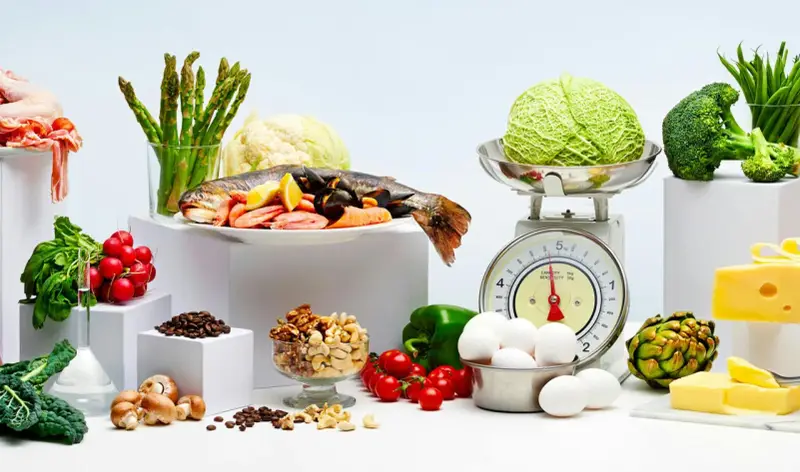 Variedad de alimentos bajos en carbohidratos: pescado, mariscos, verduras, huevos, frutos secos y queso.